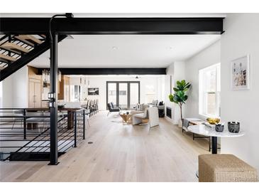 Open-concept living room with modern furnishings, natural light, and a staircase at 1880 S Adams St, Denver, CO 80210