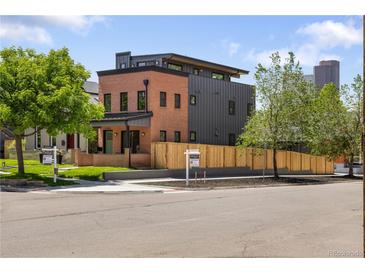 Modern home with brick and metal siding, featuring a well-manicured lawn and professional landscaping at 2395 N Emerson St, Denver, CO 80205