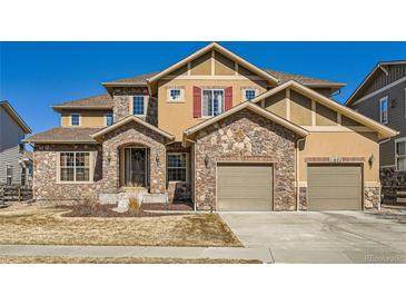 Charming two-story home featuring a stone facade, two-car garage, and well-kept lawn at 11602 Pine Canyon Dr, Parker, CO 80138
