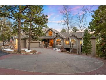 Charming home with a large circular driveway surrounded by mature pine trees and a well-maintained front yard at 30082 Troutdale Ridge Rd, Evergreen, CO 80439