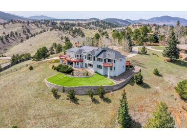 Majestic home with red accents features professional landscaping and a serene, mountainous backdrop at 260 Dekker Dr, Golden, CO 80401