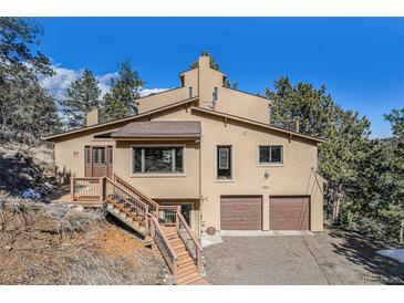 Inviting multi-level exterior with wood staircase, two car garage, and neutral stucco under a bright blue sky at 268 Cedar Rd, Golden, CO 80401