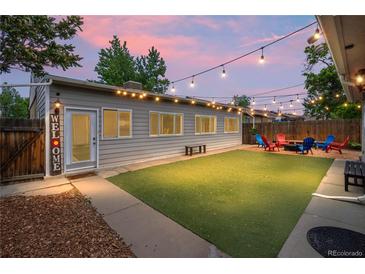 Inviting backyard features a fire pit, colorful Adirondack chairs, artificial turf and string lights at 3241 Sheridan Blvd, Wheat Ridge, CO 80212