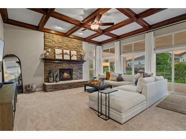 Spacious living room featuring a stone fireplace, coffered ceiling, and large windows with natural light at 27290 E Nova Cir, Aurora, CO 80016