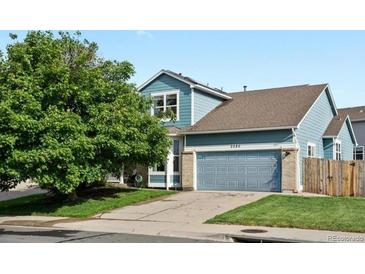 Two-story home featuring blue siding, a two-car garage, manicured lawn and mature shade tree at 2080 S Danube Ct, Aurora, CO 80013