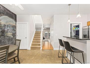 Inviting open-concept living room featuring a staircase, kitchen bar, and unique chalkboard wall at 2800 Aurora Ave # 118, Boulder, CO 80303