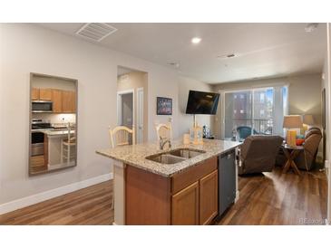 Modern kitchen with stainless steel appliances, granite countertops, and an open layout to the living area at 14341 E Tennessee Ave # 203, Aurora, CO 80012