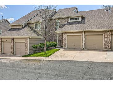 Townhome with brick and tan siding, individual garages, and landscaped front yard at 1470 S Quebec Way # 46, Denver, CO 80231