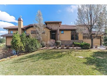 Beautiful two-story home with a tile roof, chimney, manicured lawn, and mature landscaping at 7850 Vallagio Ln, Englewood, CO 80112