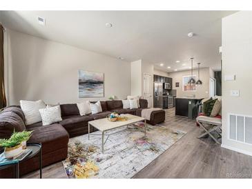 Inviting living room featuring a comfortable sectional sofa and an open layout leading into the kitchen at 1631 Aspen Meadows Cir, Denver, CO 80260