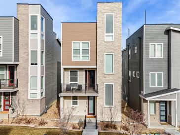 Modern three-story townhome boasts a stone facade and a charming balcony at 11487 W Grand Way, Littleton, CO 80127