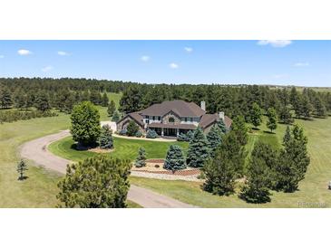 Stately two-story home on a large lot, surrounded by mature trees and landscaping, circular driveway at 36412 Paradise Cir, Elizabeth, CO 80107