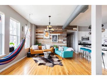 Bright living room featuring hardwood floors, modern decor, and a unique reclaimed wood accent wall at 1489 Steele St # 104, Denver, CO 80206