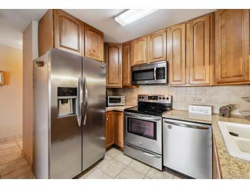 Well-equipped kitchen featuring stainless steel appliances, tile floors, and ample cabinet space at 715 S Alton Way # 5D, Denver, CO 80247