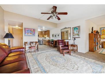 Inviting living room featuring plush seating, a ceiling fan, and views into the adjacent updated kitchen at 715 S Alton Way # 5D, Denver, CO 80247