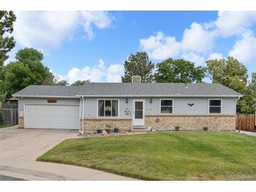 Charming single-story home with light-blue siding, brick accents, well-kept lawn, and a driveway leading to an attached garage at 6651 S Dudley Ct, Littleton, CO 80123