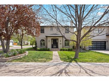 Charming two-story home with stucco exterior, well-manicured lawn, and mature trees at 2500 S Monroe St, Denver, CO 80210