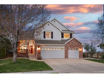 Charming two-story home featuring a well-maintained lawn and a three-car garage at sunset at 13804 Quail Ridge Dr, Broomfield, CO 80020
