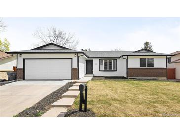 Charming single-Gathering home featuring a manicured front lawn, attached garage, and brick accents at 558 S Field Ct, Lakewood, CO 80226