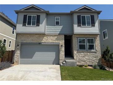 Charming two-story home with a stone facade, attached garage, and well-manicured lawn at 16651 W 93Rd Ave, Arvada, CO 80007