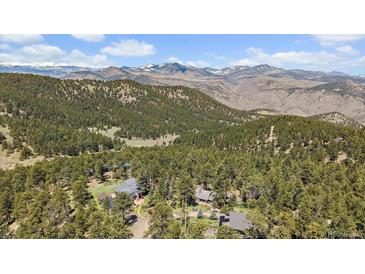 Scenic aerial view of mountain home nestled among trees with mountain range in the background at 513 Mt Blue Sky Rd, Golden, CO 80401