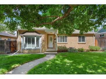 Charming brick home with bay window, lush lawn, and mature tree providing shade at 1080 S Garfield St, Denver, CO 80209