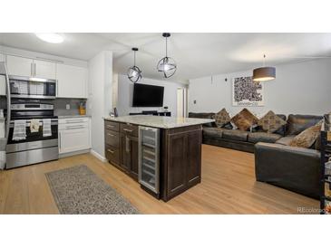Open-concept living room featuring a kitchen island with a built-in wine cooler and comfortable leather seating at 1260 York St # 102, Denver, CO 80206