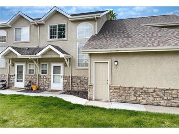 Charming townhome featuring a stone facade, well-maintained lawn, and inviting entrance, offering a welcoming curb appeal at 2247 Coronado Pkwy N #D, Denver, CO 80229