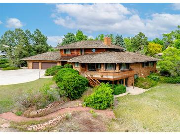 Unique, multi-story home featuring a wood and brick exterior, complemented by mature landscaping at 1961 S Xenia Ct, Denver, CO 80231