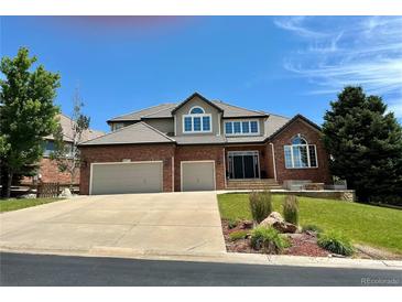 Beautiful two-story brick home featuring an attached two-car garage and a professionally landscaped front yard at 6577 Esperanza Dr, Castle Pines, CO 80108