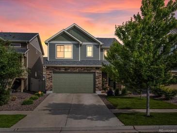 Two-story home featuring stone accents, an attached two-car garage, and professionally landscaped yard during a colorful sunset at 5358 Ventura St, Denver, CO 80249