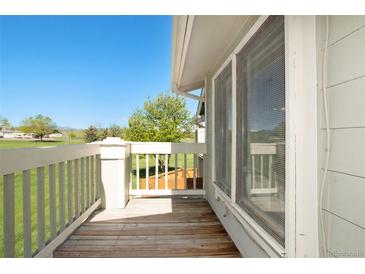 Outdoor deck with white railings overlooking a lush green lawn and trees under a clear blue sky at 6962 W 87Th Way # 270, Arvada, CO 80003