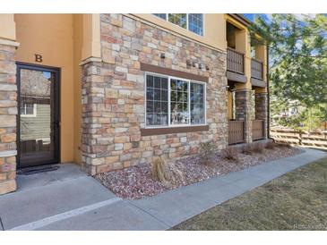 Attractive multi-Gathering unit with stone accents, walkway, door, and a view of the well-maintained landscape at 9896 W Freiburg Dr # 1B, Littleton, CO 80127