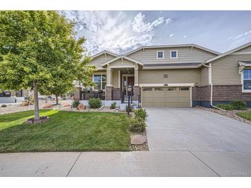 Charming two-story home featuring a well-manicured lawn and inviting front porch with decorative brick accents at 14883 Roslyn Way, Thornton, CO 80602