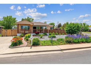 Charming home featuring a welcoming front porch and beautifully landscaped front yard with vibrant flowers at 2196 W 56Th Ave, Denver, CO 80221