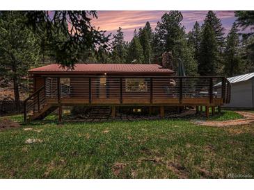 Charming log cabin with a spacious deck surrounded by lush greenery and a beautiful sunset at 11080 S Deer Creek Rd, Littleton, CO 80127