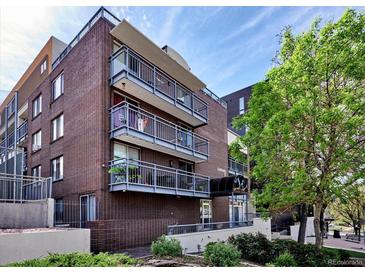 Multi-story brick building with multiple balconies in an urban area under a clear blue sky at 830 N Sherman St # 205, Denver, CO 80203