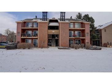 Three-story condo building with brick facade, balconies, and snow-covered lawn at 4899 S Dudley St # 5H, Littleton, CO 80123