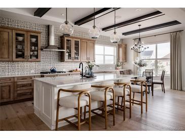 Bright kitchen features an island with seating, patterned backsplash, wood cabinets, stainless steel appliances, and modern lighting at 27608 E Ottawa Ave, Aurora, CO 80016