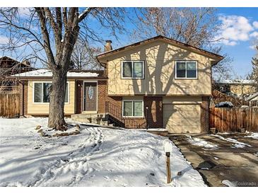 Ranch style home with brick accents and a two-car garage, nestled on a tree-lined street at 8653 W 67Th Ave, Arvada, CO 80004