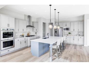 Bright kitchen boasts stainless steel appliances, large island with bar seating and modern lighting at 27500 E Lakeview Dr, Aurora, CO 80016