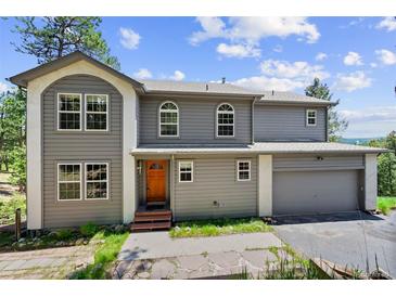 Charming two-story home featuring a well-manicured lawn, complemented by an attached two car garage at 6904 Sprucedale Pkwy, Evergreen, CO 80439