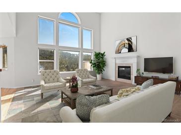 Bright living room boasts a fireplace, large windows with views and plush seating at 6904 Sprucedale Pkwy, Evergreen, CO 80439