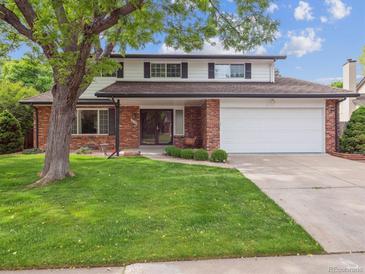 Charming two-story brick home with a well-manicured lawn and mature tree at 6898 W Nova Dr, Littleton, CO 80128