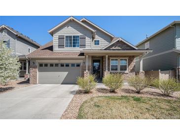 Charming two-story home featuring stone accents, gray siding and a well manicured front lawn at 7121 W Asbury Pl, Lakewood, CO 80227