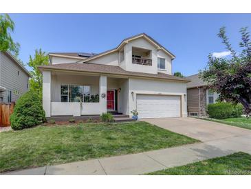 Inviting two-story home featuring a red front door, a balcony, and a well-maintained lawn at 5757 W Alamo Dr, Littleton, CO 80123