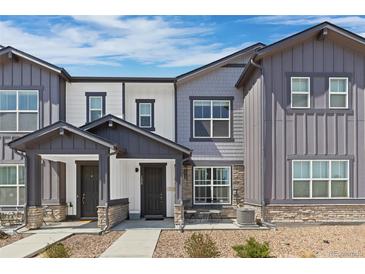 Charming townhome featuring a covered entryway, stone accents, and manicured landscaping at 132 Ambrose St, Erie, CO 80516