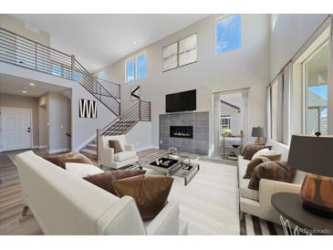 Bright, open living room with fireplace, high ceilings, and modern staircase at 4880 River Landing Ave, Firestone, CO 80504