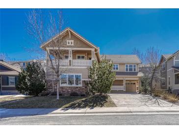 Two story home with stone accents, balcony, covered porch, driveway and landscaping against a clear blue sky at 5078 Zion Ct, Castle Rock, CO 80109