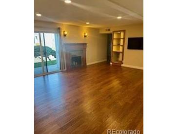 Bright living room with hardwood floors, fireplace, and sliding glass door to the outside at 7665 E Eastman Ave # 110C, Denver, CO 80231